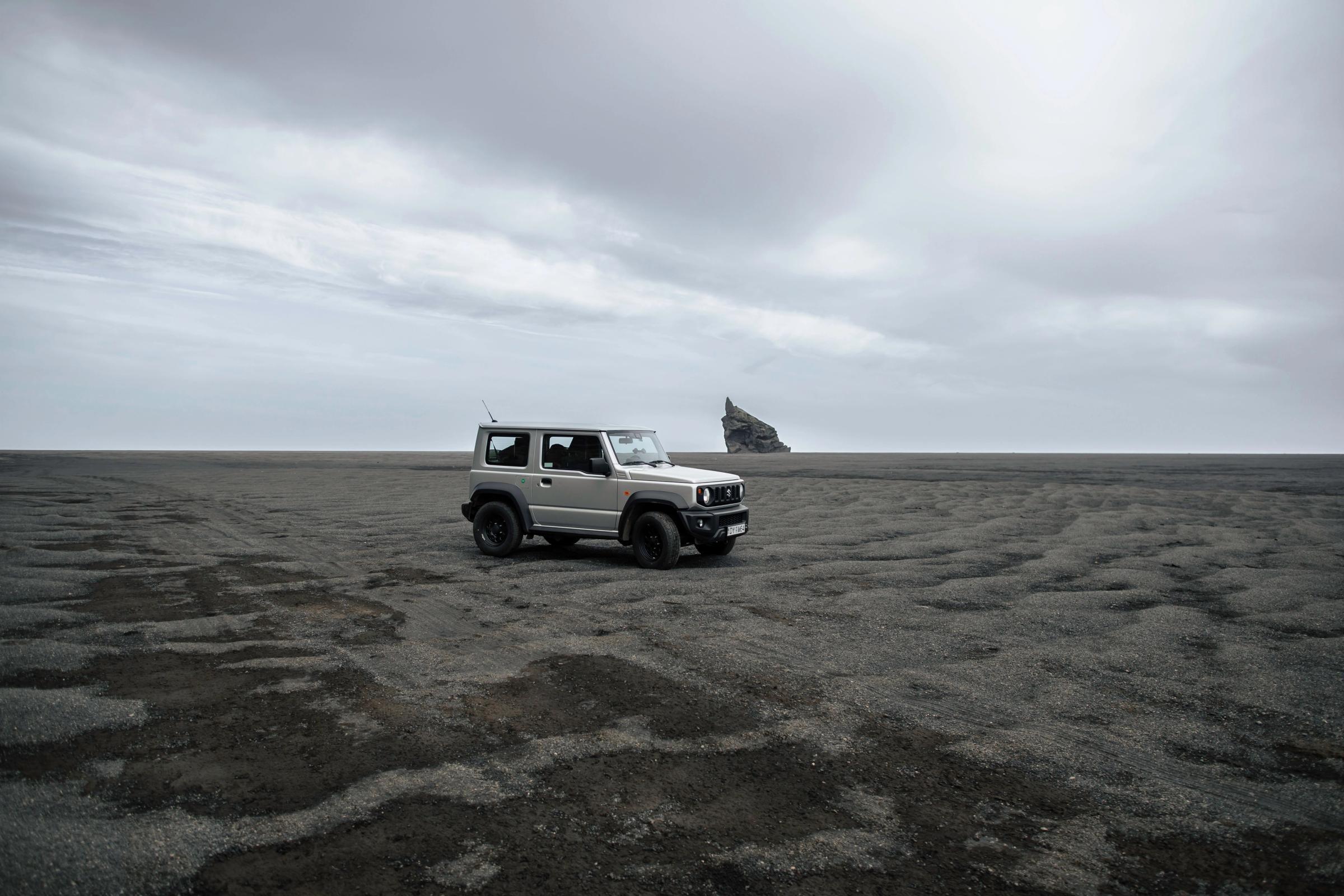 4x4 rental car Suzuki Jimny parked on a black sand beach in Iceland