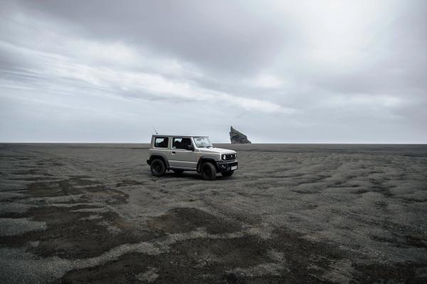 Suzuki Jimny rental car Iceland 4x4 rental car Suzuki Jimny parked on a black sand beach in Iceland