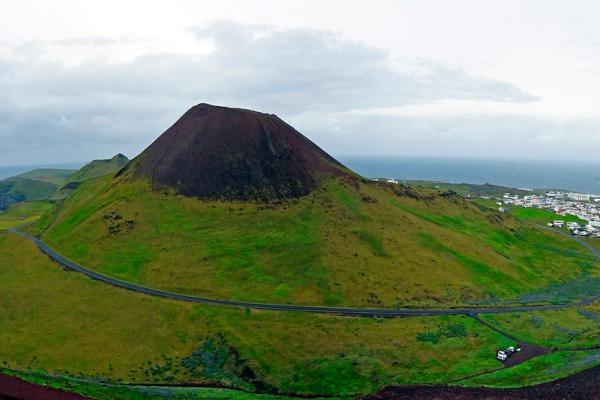 an aerial view of Eldfell Volcano with a city in the background .