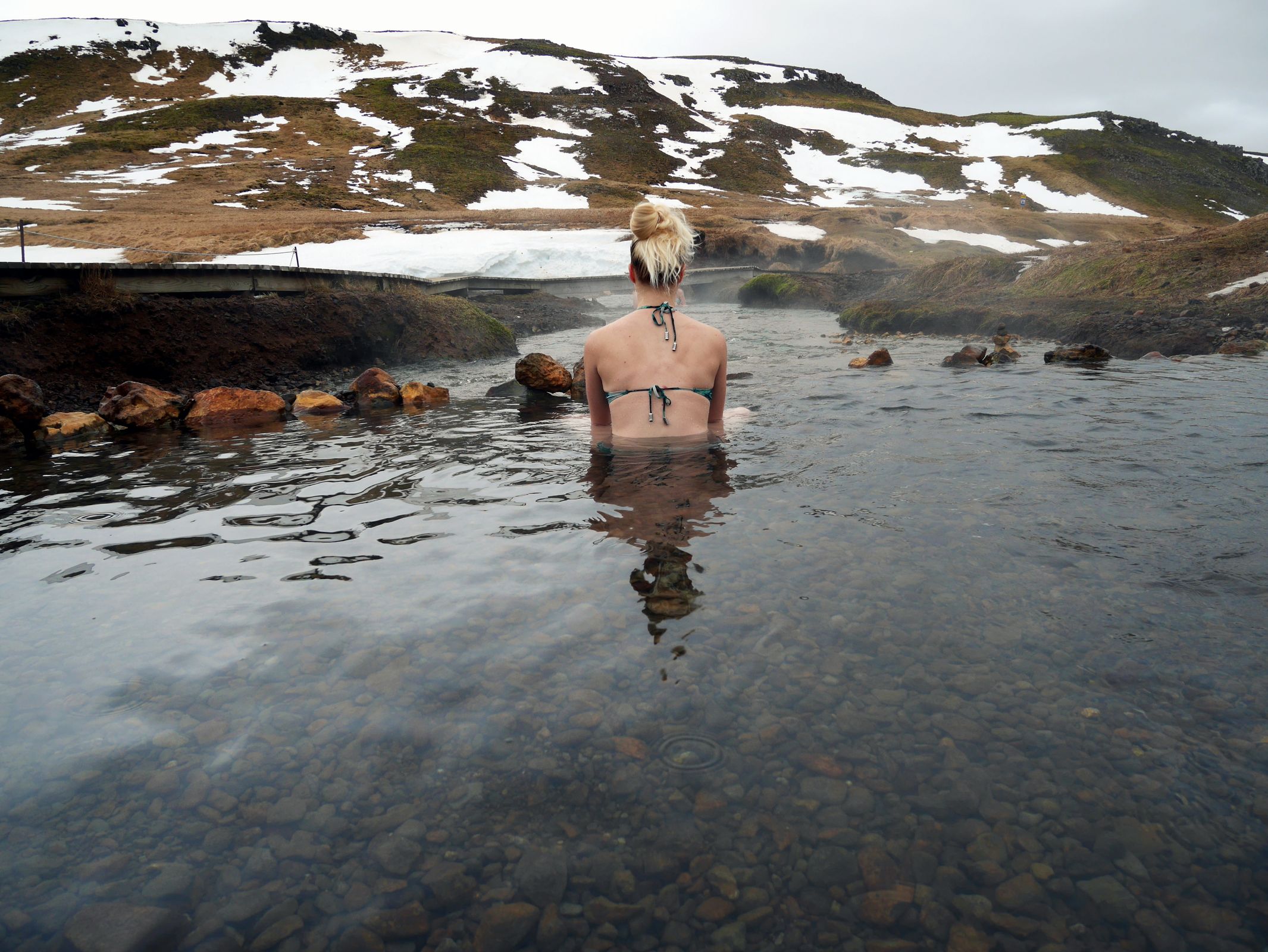 a woman in a bikini is swimming in a river in a swimsuit in iceland.