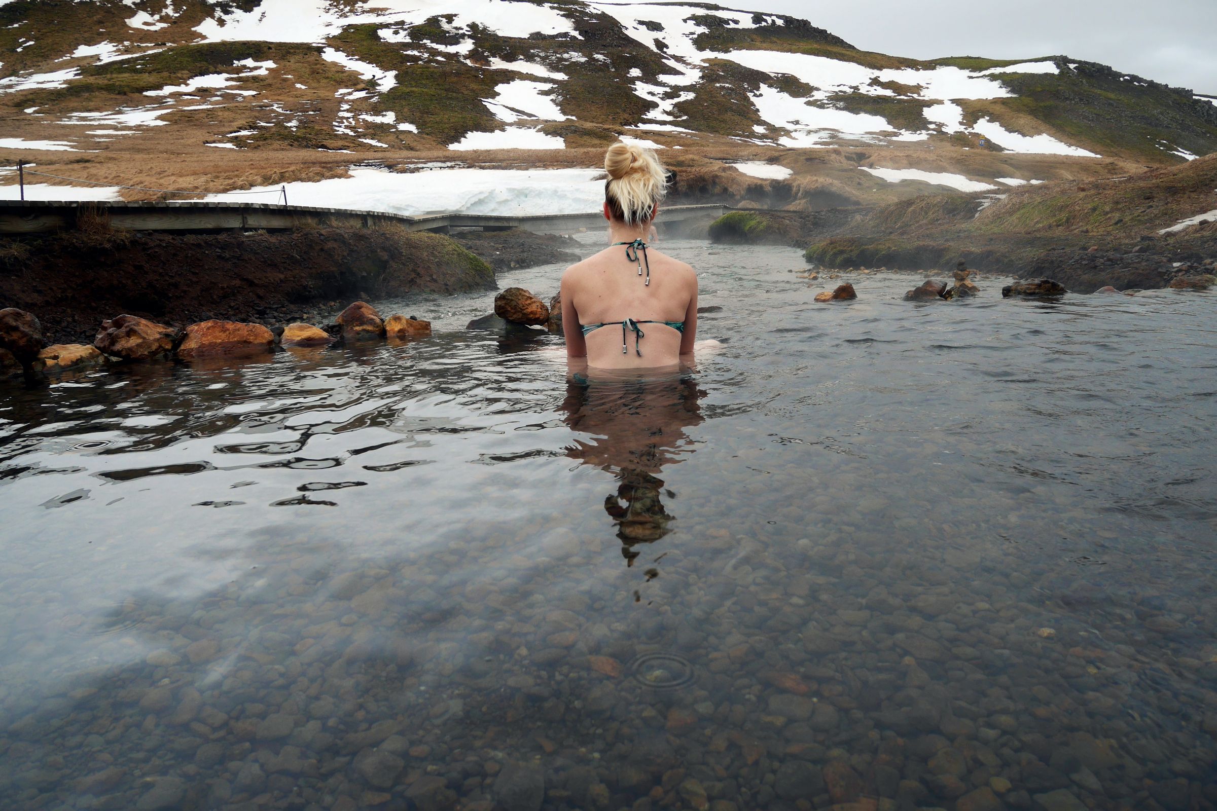 a woman in a bikini is swimming in a river in a swimsuit in iceland.