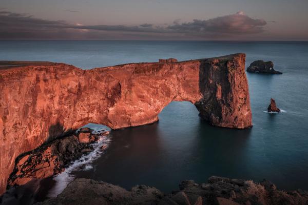 The Arch With The Hole, Iceland view on the beautiful rock arch at Dyrholaey, Iceland. Dyrholaey means the hill island with the door hole