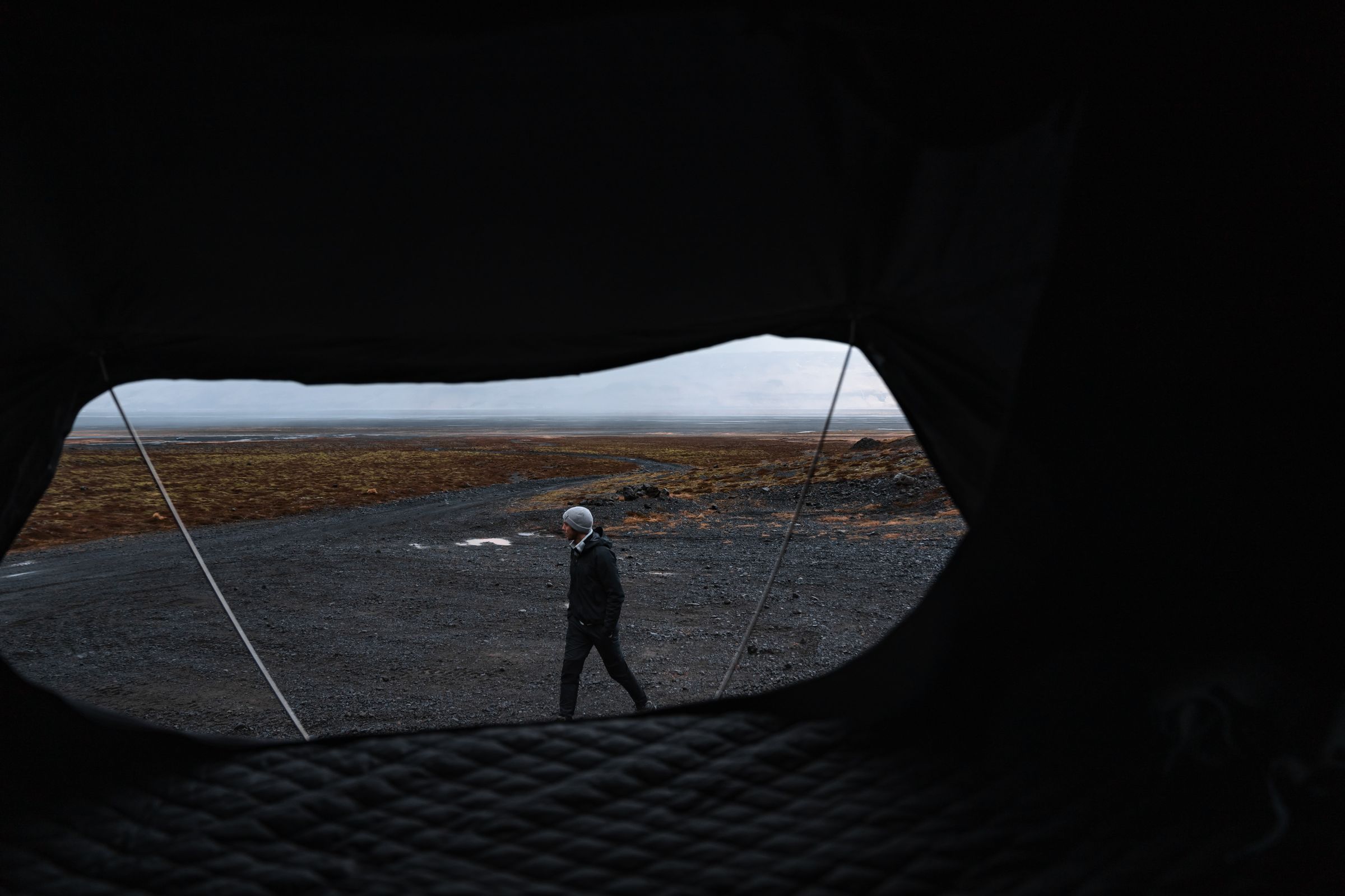 Útsýni yfir mölina úr tjaldi Útsýni innan úr þaktjaldi yfir manneskju sem gengur um opið malarsvæði