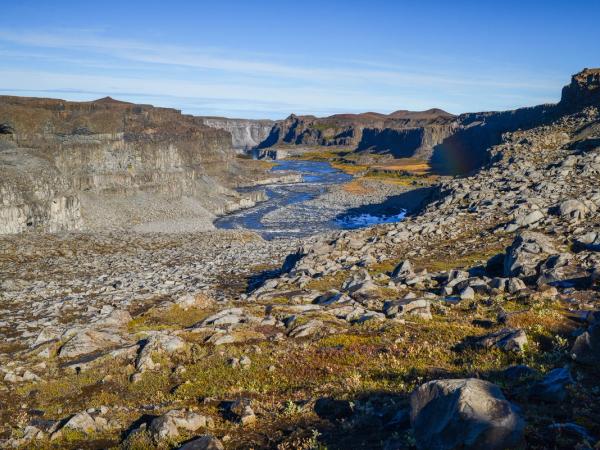 un río fluyendo a través de un valle rocoso en las montañas.