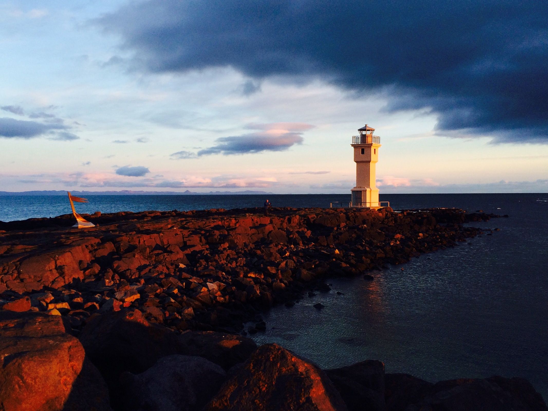 un delgado faro blanco junto al mar con la luz cálida del atardecer