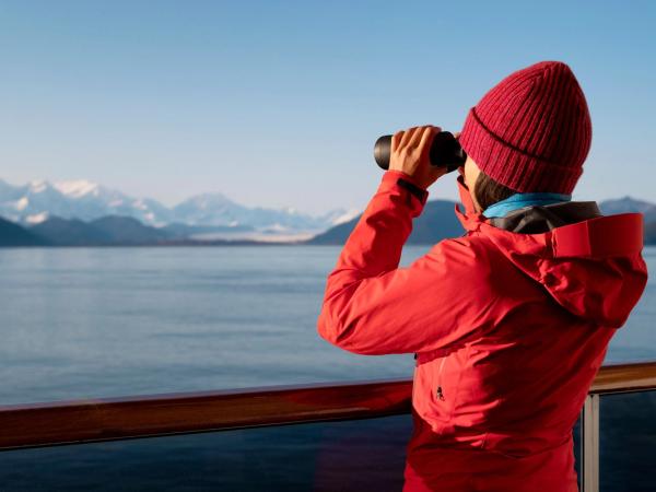 una mujer con una chaqueta roja está mirando a través de unos binoculares en un barco.