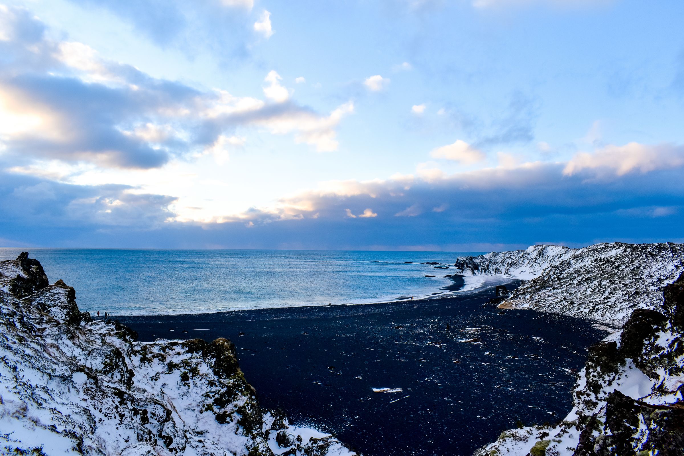 playa de arena negra Djupalonssandur en invierno con partes cubiertas de nieve