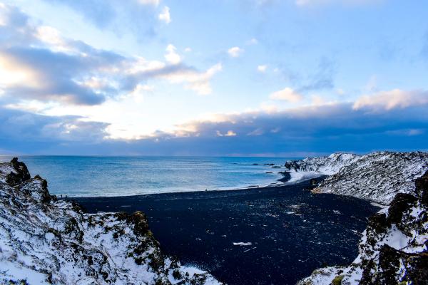 playa de arena negra Djupalonssandur en invierno con partes cubiertas de nieve