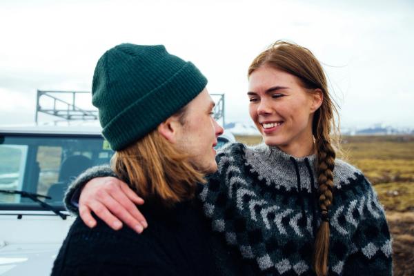 a man and a woman are standing next to each other in front of a car .