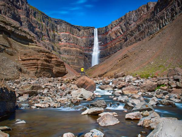 Hengifoss waterfall with a hiker admiring it