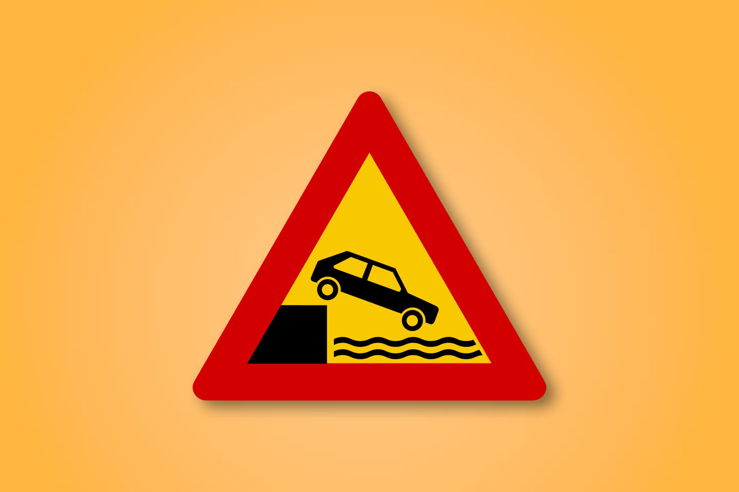 a red and yellow triangle sign with a car going down a hill into the water .