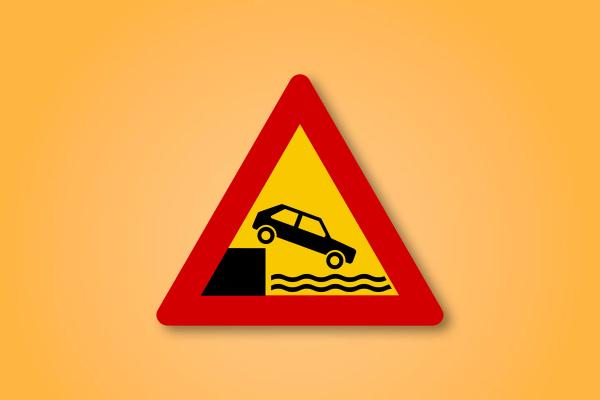 a red and yellow triangle sign with a car going down a hill into the water .