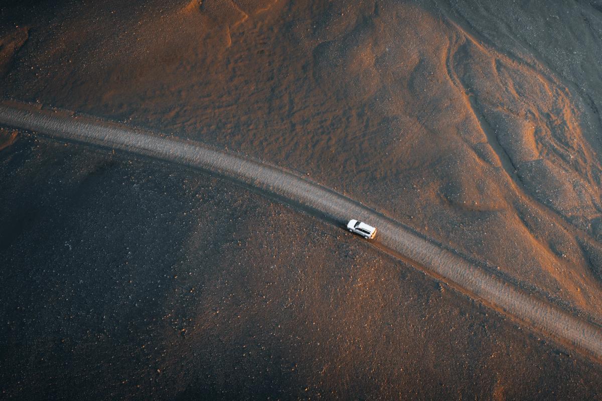 Toyota Land Cruiser from above on a narrow road crossing dark sand