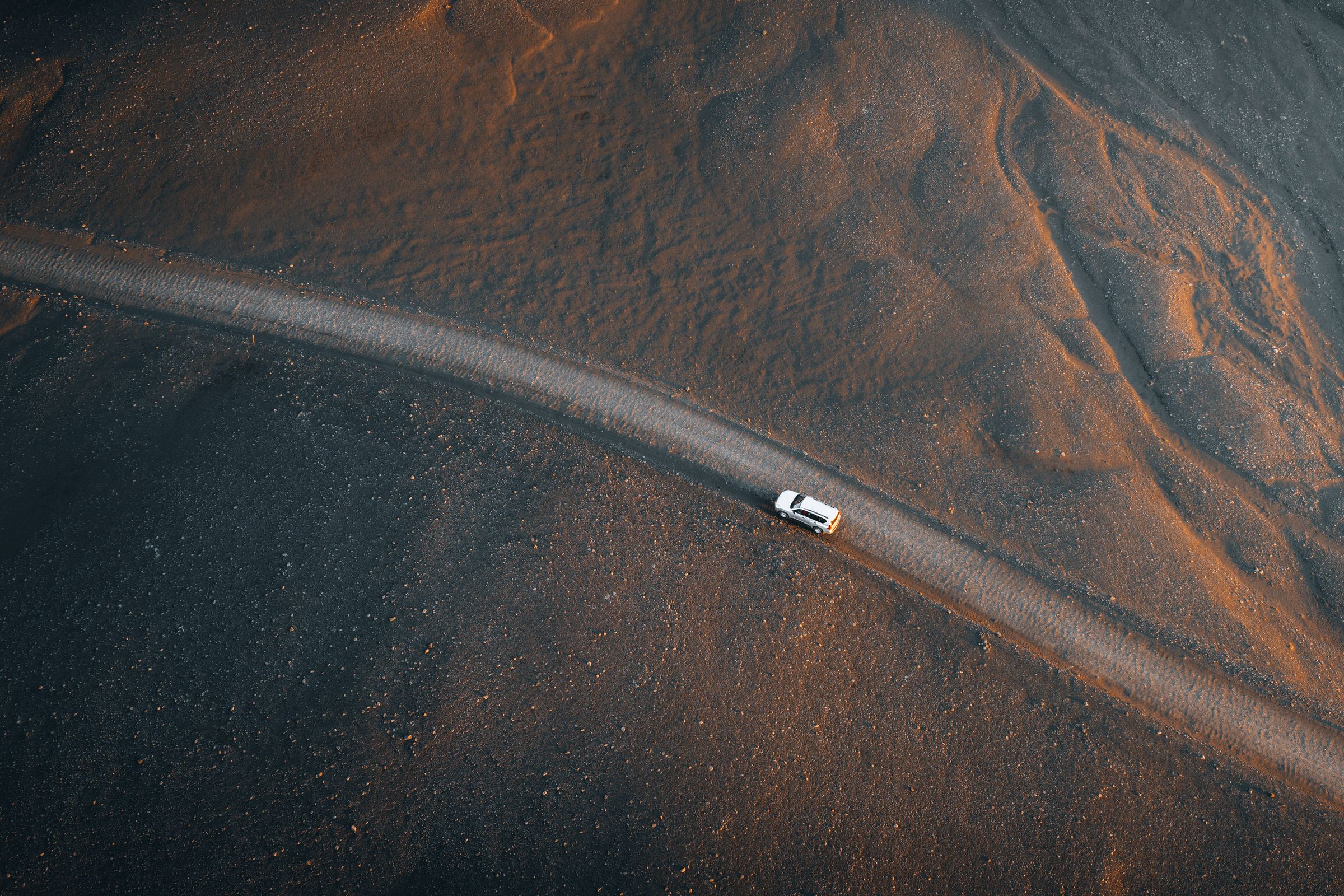 Land Cruiser aus der Vogelperspektive Toyota Land Cruiser aus der Vogelperspektive auf einer schmalen Straße, die durch dunklen Sand führt