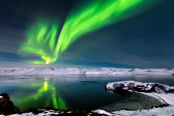 the aurora borealis is reflected in the water of a lake .