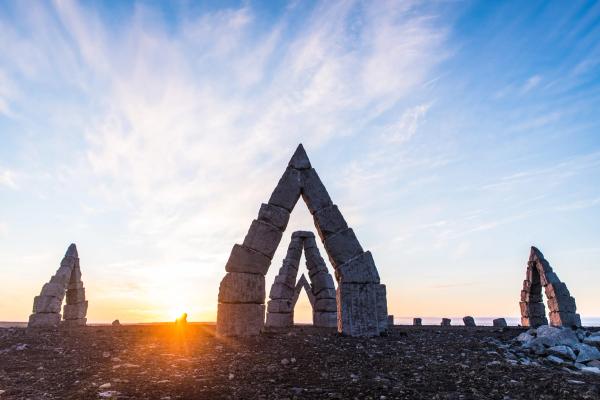 the sun is setting behind a stone sculpture in the shape of a mountain right outside raufarhöfn Iceland..