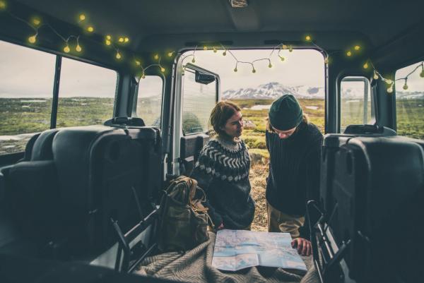 a man and a woman are looking at a map in the back of a car .