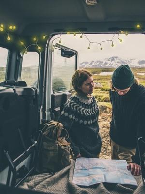 a man and a woman are looking at a map in the back of a car .