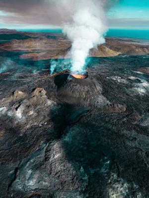 an aerial view of volcano Fagradalsfjall erupting with smoke coming out of it.