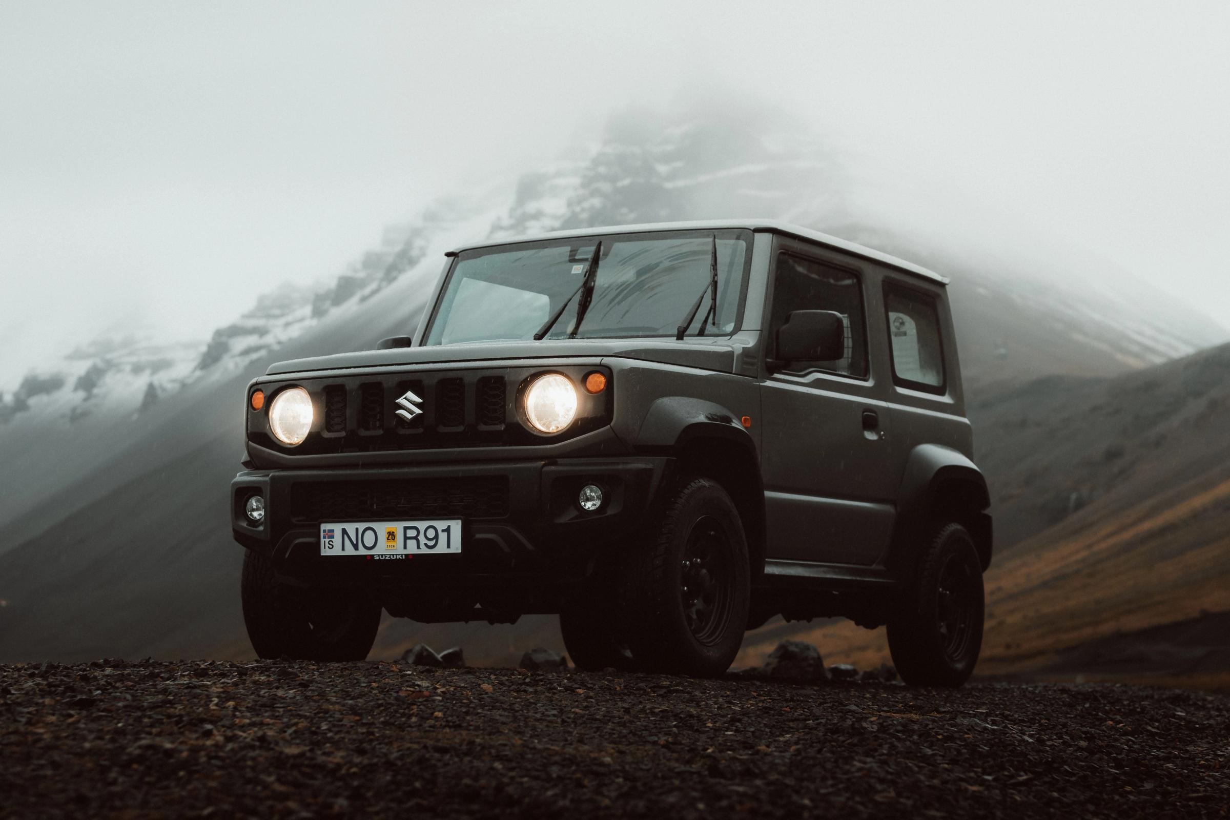 Suzuki Jimny 4x4 automatique garé devant des montagnes embrumées, voiture de location automatique en Islande