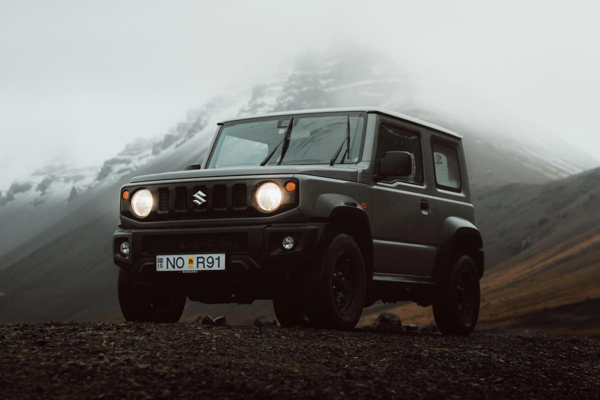 Suzuki Jimny 4x4 automatique garé devant des montagnes embrumées, voiture de location automatique en Islande