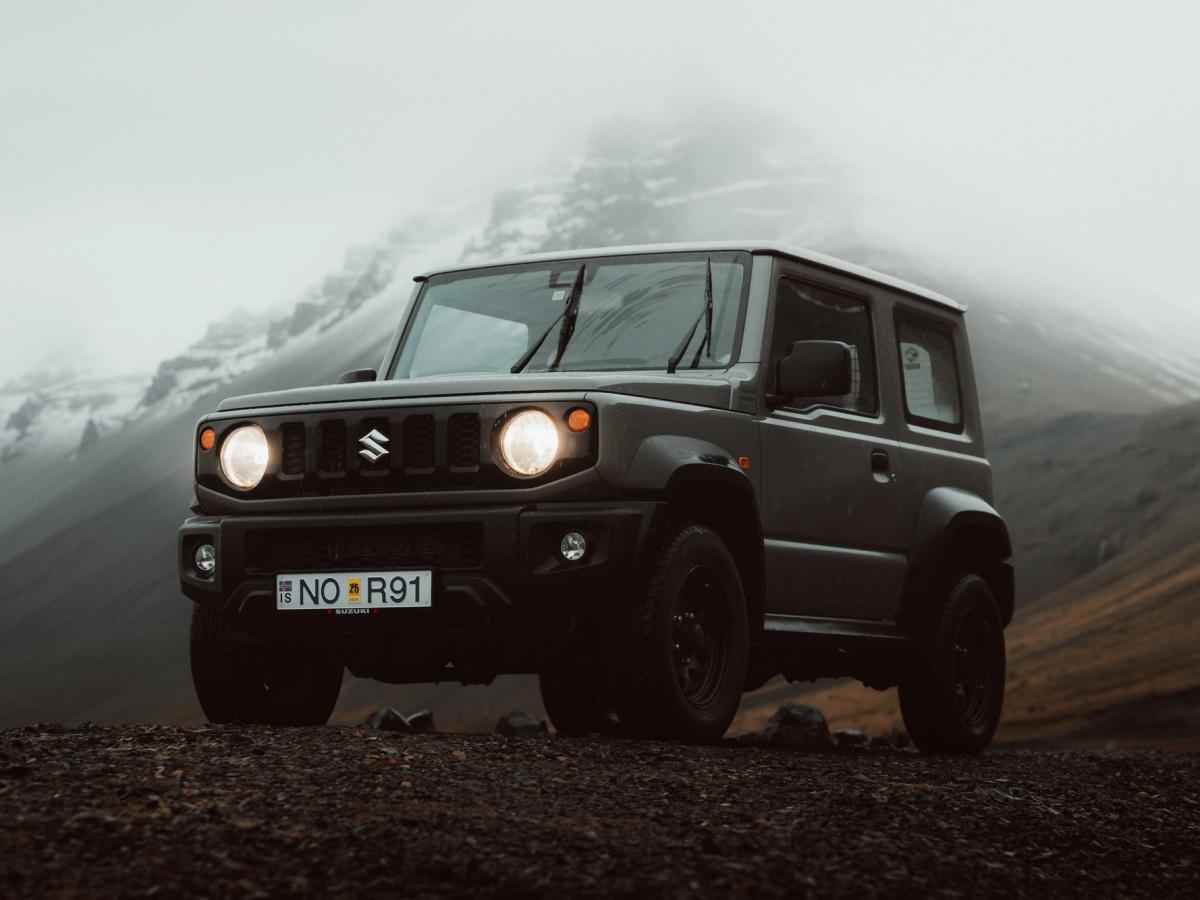 Jimny automatique Mountain Fog Suzuki Jimny 4x4 automatique garé devant des montagnes embrumées, voiture de location automatique en Islande