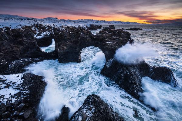 Olas chocando contra un arco de piedra sobre el mar