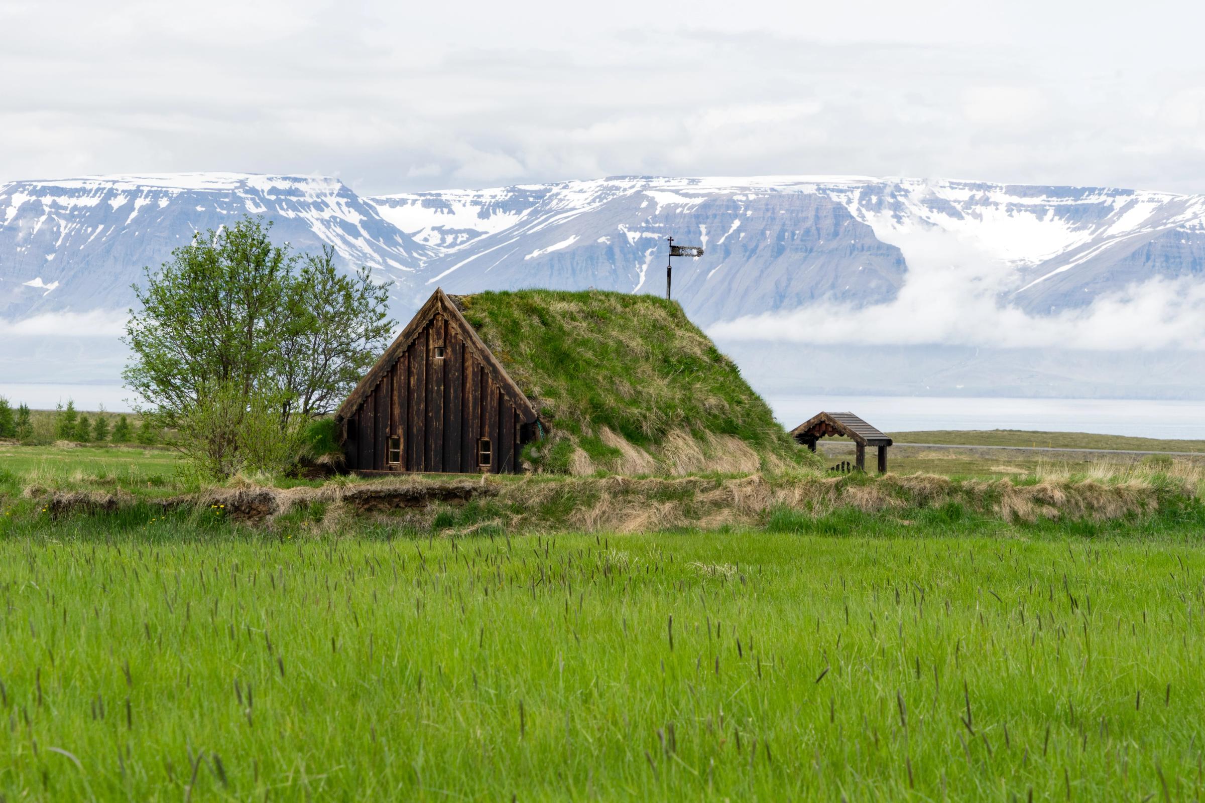 a small hut is sitting on top of a grassy hill in the middle of a field .