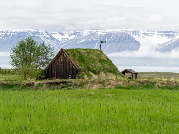 a small hut is sitting on top of a grassy hill in the middle of a field .