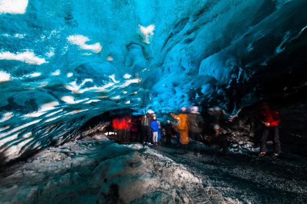 a group of people are standing inside of an ice cave .