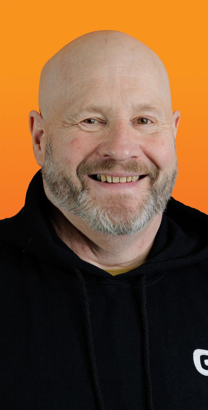 a bald man with a beard wears a black hoodie with the letter g on it