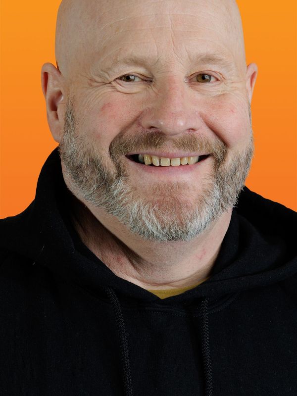 a bald man with a beard wears a black hoodie with the letter g on it