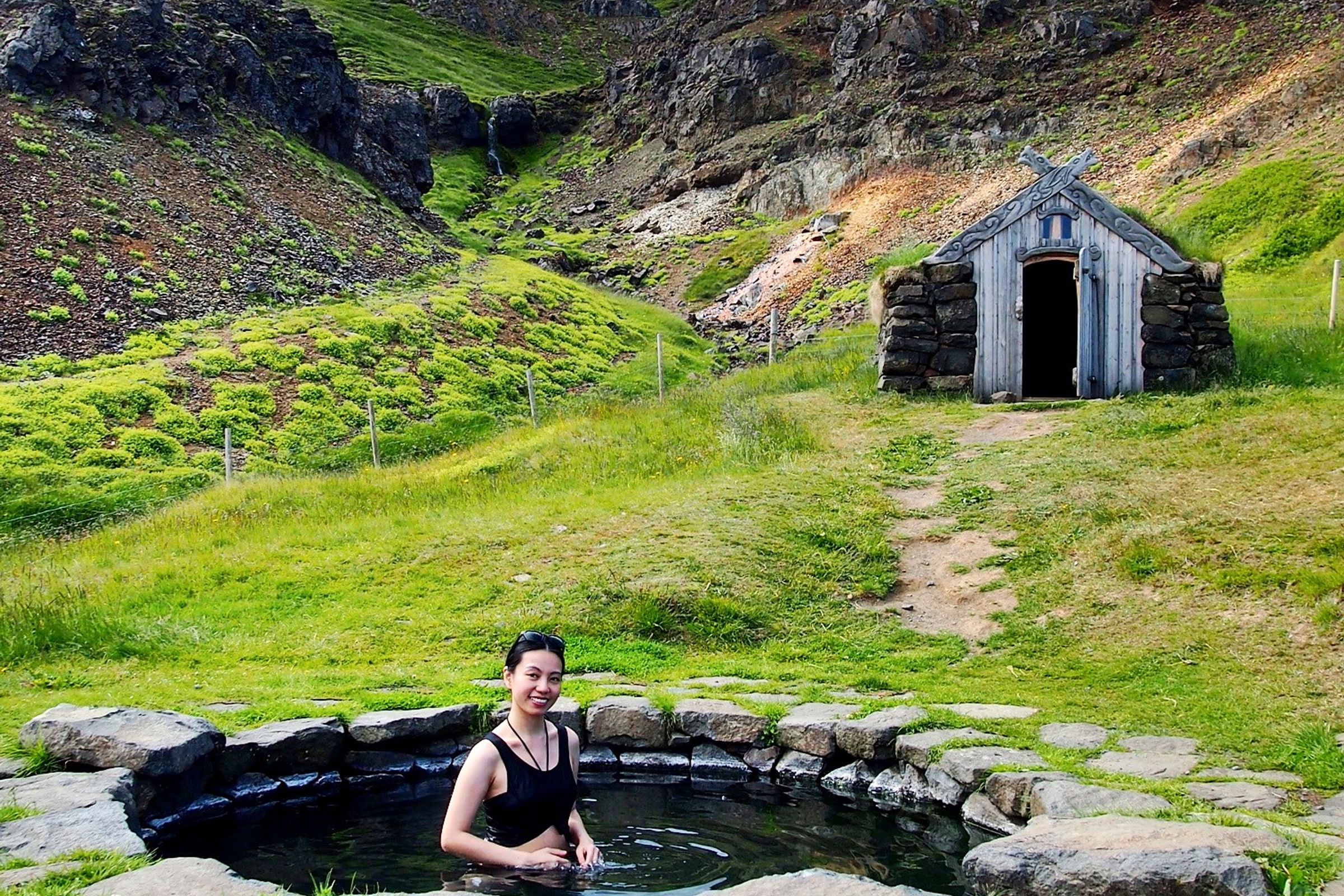 a woman inside a small rounded pool with a cottage on the background