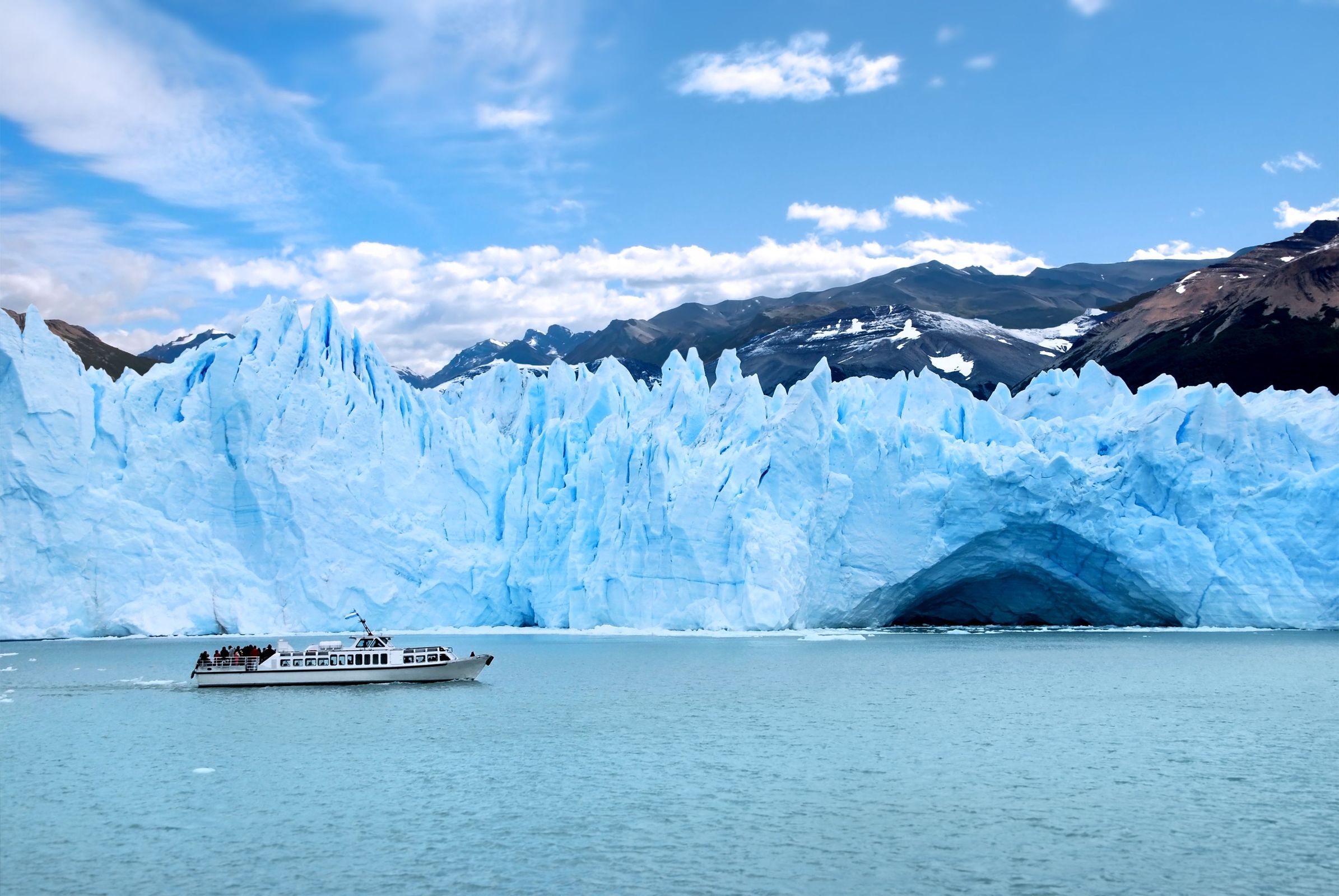 a boat in front of a big ice wall