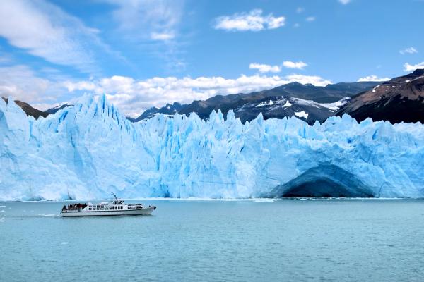 a boat in front of a big ice wall