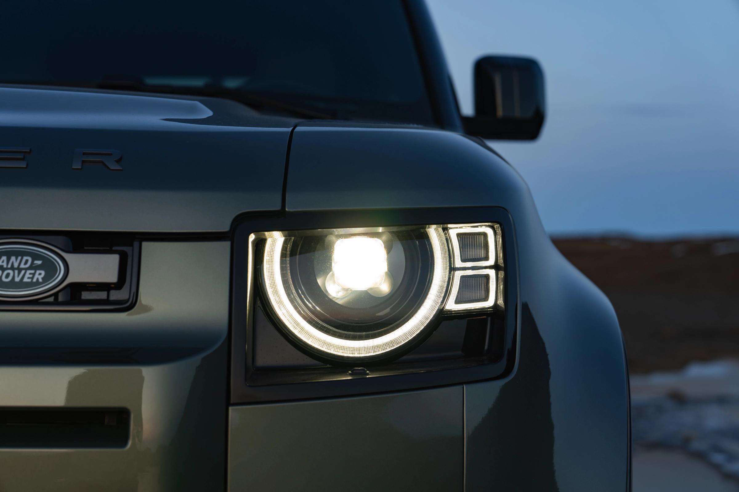 Primer plano del faro LED encendido de un Land Rover Defender al anochecer, un coche de alquiler de Go Car Rental Iceland