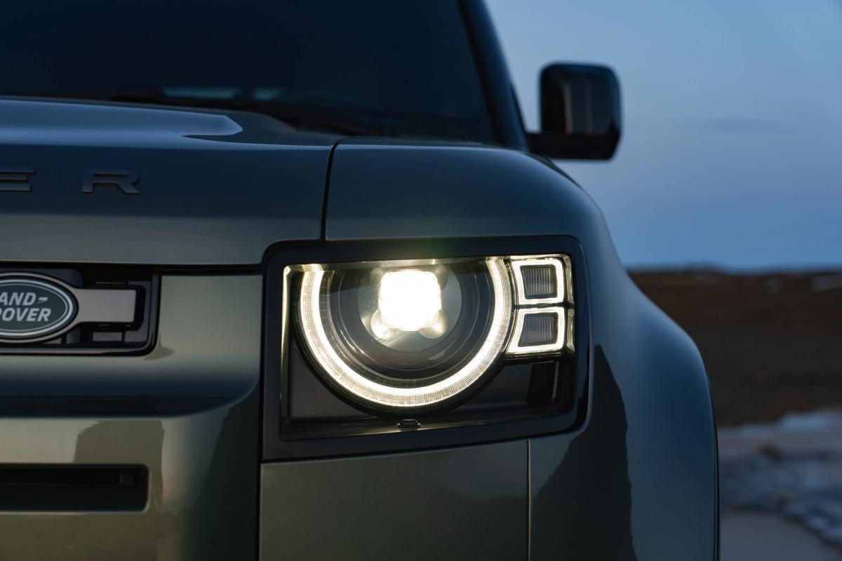 Primer plano del faro LED encendido de un Land Rover Defender al anochecer, un coche de alquiler de Go Car Rental Iceland