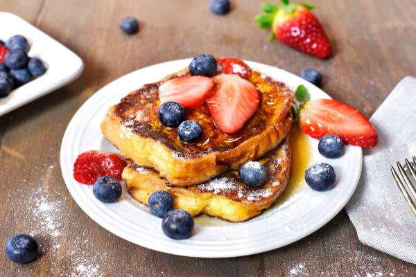 french toast with strawberries and blueberries on a white plate .