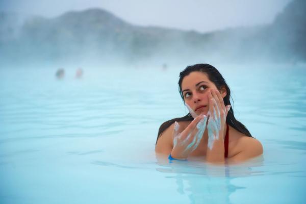 a woman is washing her face in a hot spring .