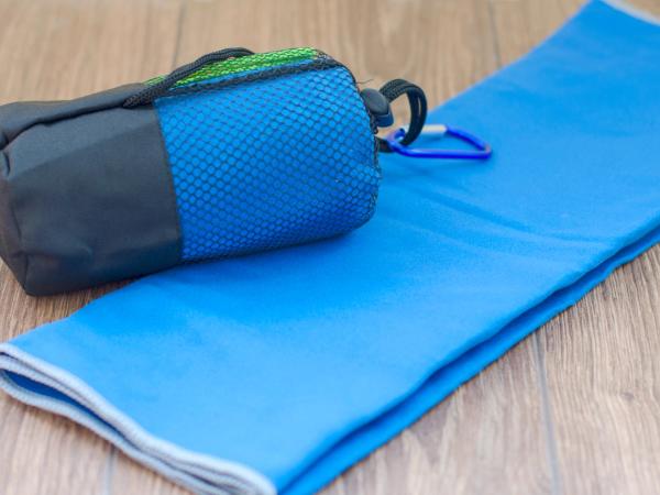 a blue towel and a bag with a carabiner on a wooden table .