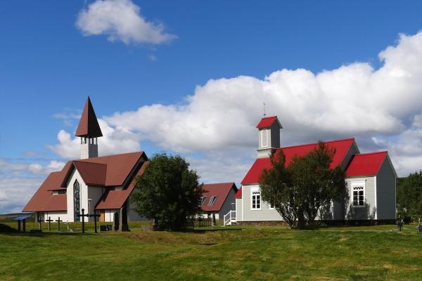 Deux églises aux toits rouges sont situées côte à côte dans un champ herbeux à Reykholt en Islande.