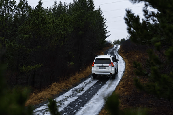 a white toyota suv camper is driving down a snowy road in iceland.