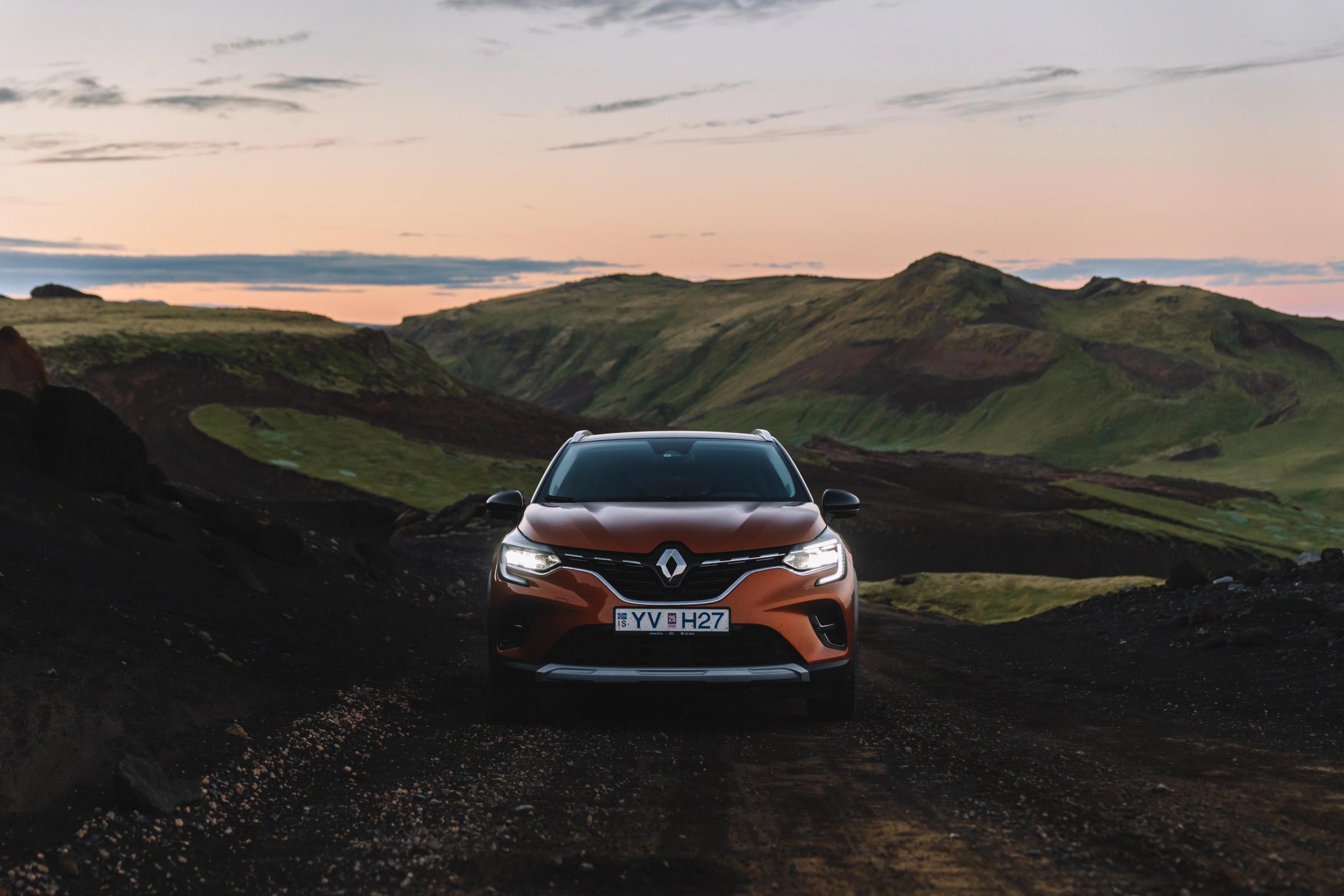 Vista frontal del Renault Captur Vista frontal de un Renault Captur aparcado en un camino de grava entre colinas verdes al atardecer