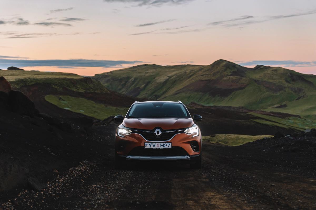 Renault Captur front view parked on a gravel road between green hills at dusk