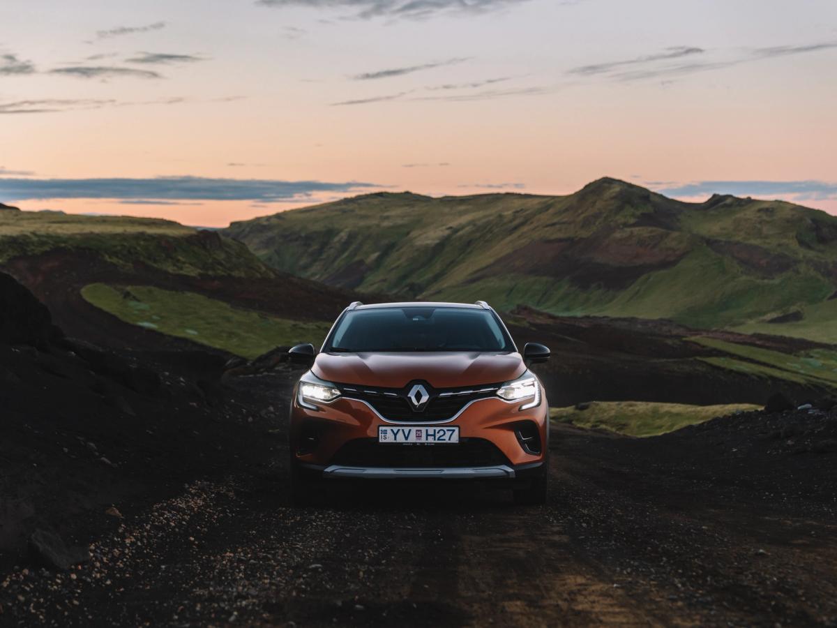 Vista frontal del Renault Captur Vista frontal de un Renault Captur aparcado en un camino de grava entre colinas verdes al atardecer