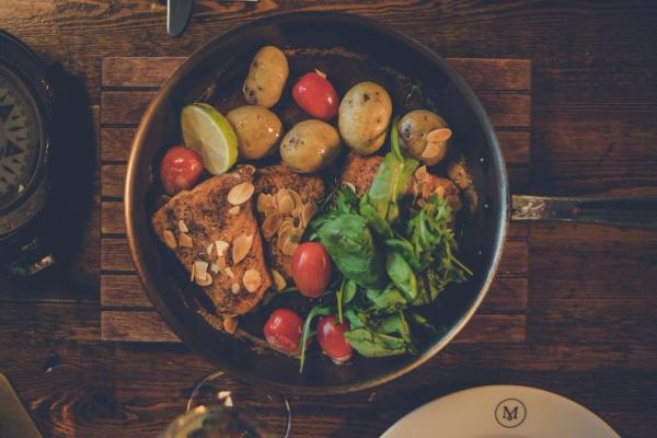 a pan filled with meat and vegetables on a wooden table .