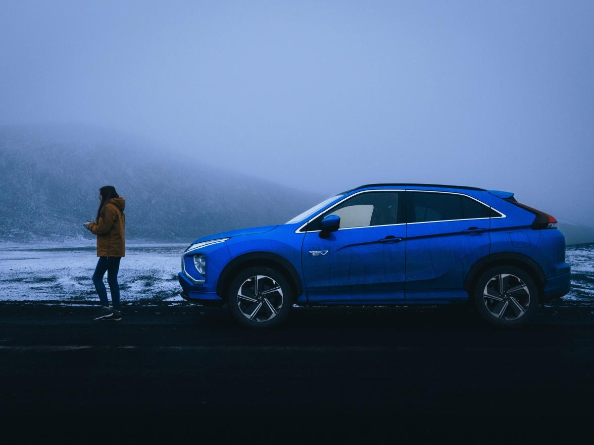 Mitsubishi Eclipse Cross al borde de una carretera con niebla Mitsubishi Eclipse Cross estacionado al borde de la carretera con una persona de pie cerca en medio de una niebla densa