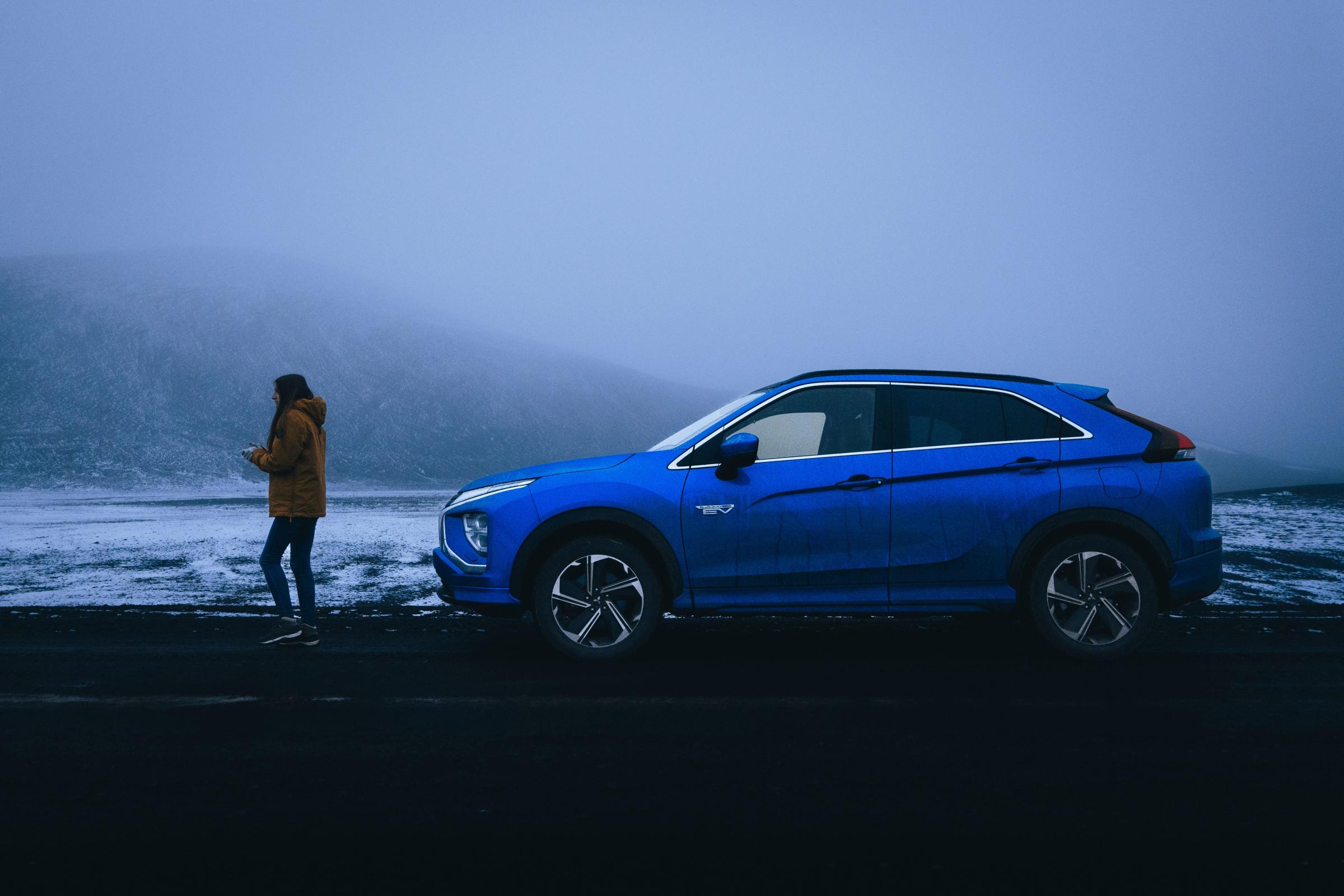 Mitsubishi Eclipse Cross al borde de una carretera con niebla Mitsubishi Eclipse Cross estacionado al borde de la carretera con una persona de pie cerca en medio de una niebla densa