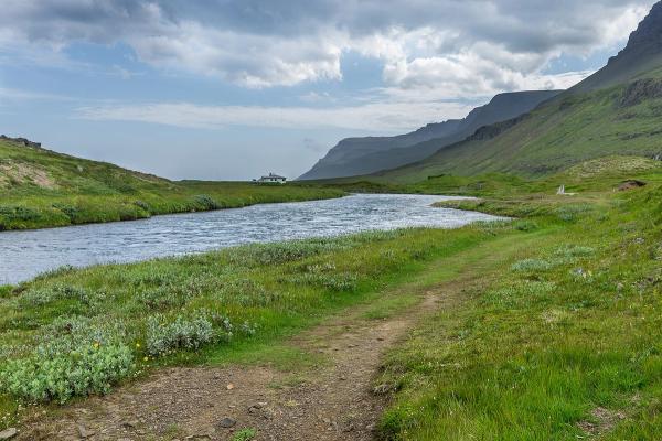 un río fluye a través de un campo herboso en las montañas.