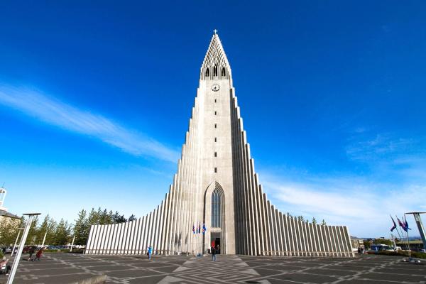 Hallgrímskirkja church, a tall, grey modernist building with a fluted facade, under a bright blue sky.
